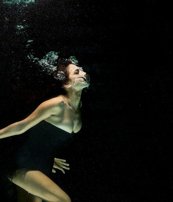 Woman in a calm, fluid motion pose against a dark background.